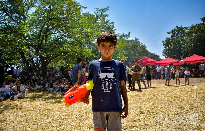 کودکی در جشن وارداوار ارمنستان با یک تفنگ آبی دردست جلوی دوربین ایستاده